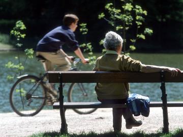 Bejaarde vrouw buiten op een rustbank in een park